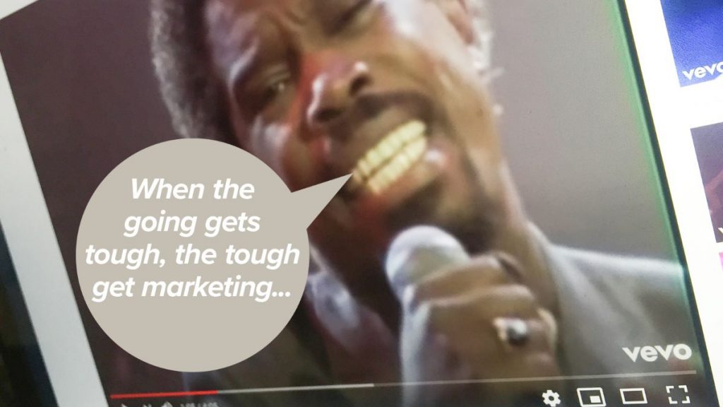 Close-up of a person singing into a microphone, with a speech bubble saying, When the going gets tough, the tough get marketing... Glued to their passion, they inspire like a branding agency in Warwickshire. The video interface shows play and volume buttons.