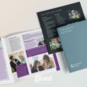 An assortment of Sanctuary Group brochures and a booklet, crafted by the renowned branding agency Glued in Warwickshire, are spread out. They showcase text, images of people, and titles like The year in summary and Our vision and values, representing their impeccable glued marketing strategy.