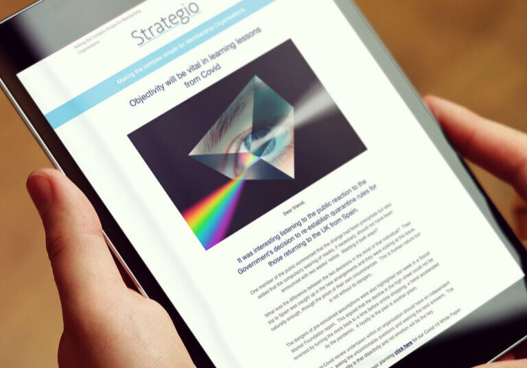 A person holds a tablet displaying a Strategio webpage with a headline about learning lessons from Covid. The screen shows a graphic of a prism splitting light into a rainbow, with the Glued Limited logo in the top corner—proudly representing the branding expertise from Warwickshire.